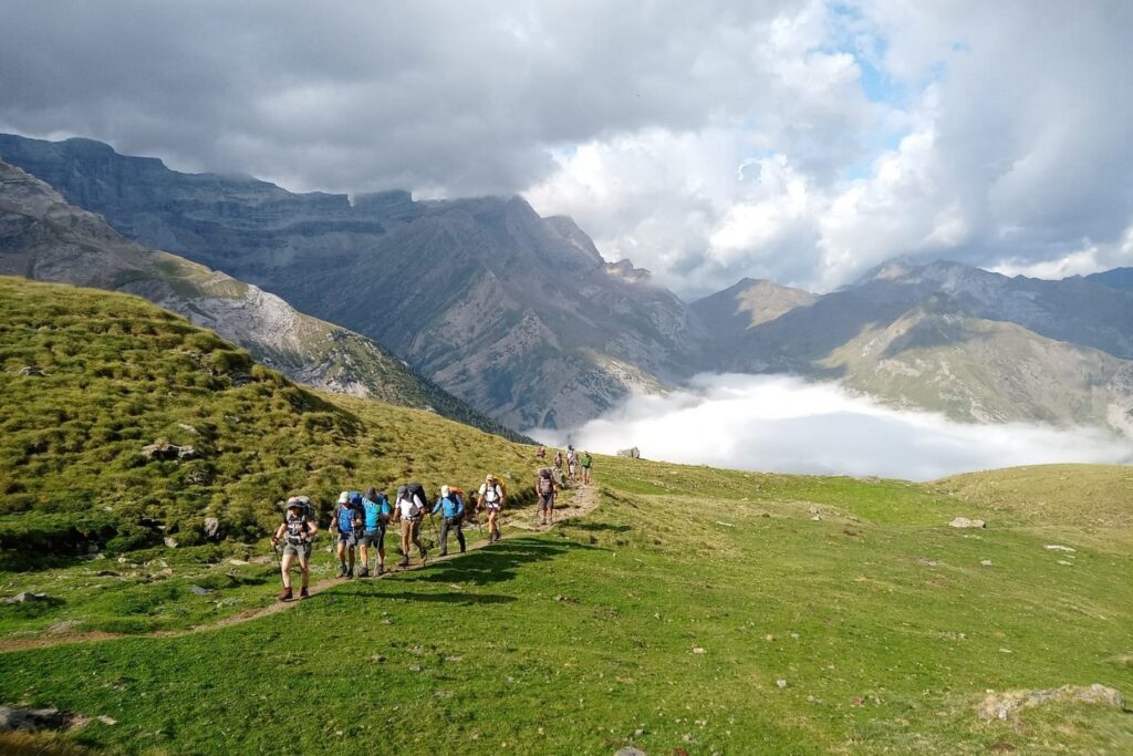 Groupe de randonneurs sur un sentier de la haute randonnée pyrénéenne avec leur guide