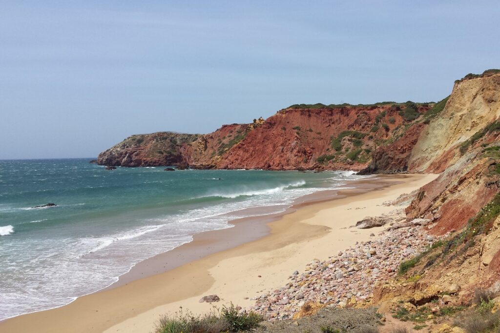 Paysage de bord de mer avec du sable sur la plage et au loin des paroies rouges