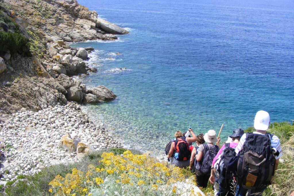 Paysage de bord de mer, avec un groupe de randonneurs qui descendent vers la plage