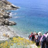 Paysage de bord de mer, avec un groupe de randonneurs qui descendent vers la plage