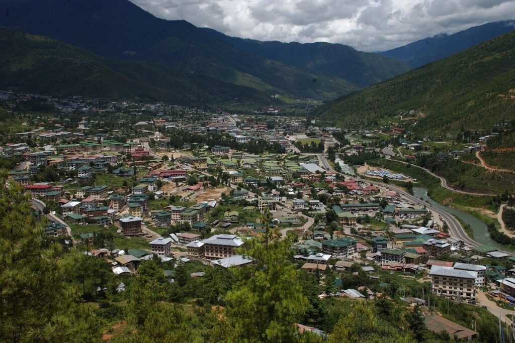 Paysage citadin avec une ville en contrebas encadrée de sommets et de végétation au Bouthan