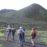 groupe de randonneurs sur un chemin de terre noire dû à la présence de volcans lors d'une randonnée vers le mont Corona dans les canaries