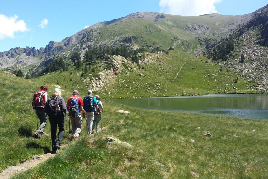 Randonneurs sur un sentier se dirigeant vers un lac, lors d'une randonnée en Andorre.