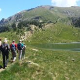 Randonneurs sur un sentier se dirigeant vers un lac, lors d'une randonnée en Andorre.