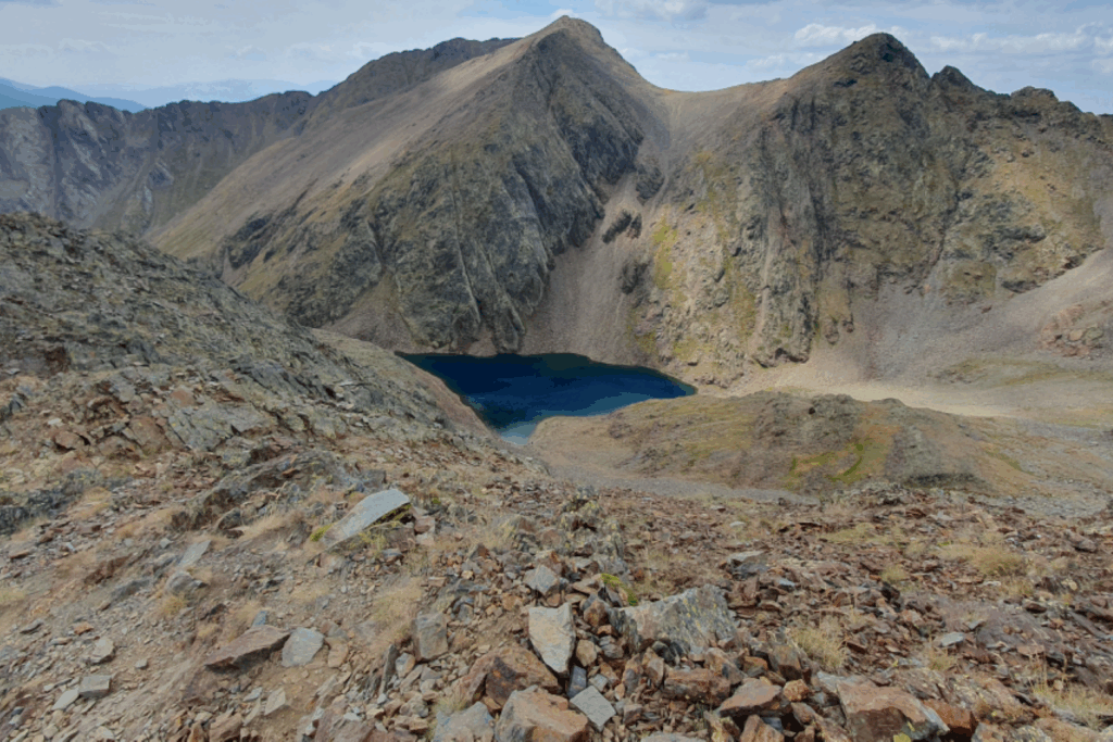 Lac de montagne entouré de montagnes avec des roches orangées.
