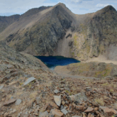 Lac de montagne entouré de montagnes avec des roches orangées.