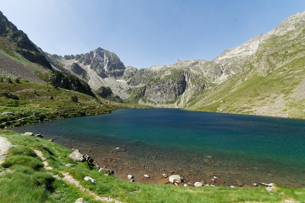 Lac de montagne avec en fond les sommets encadrés de végétation