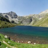 Lac de montagne avec en fond les sommets encadrés de végétation