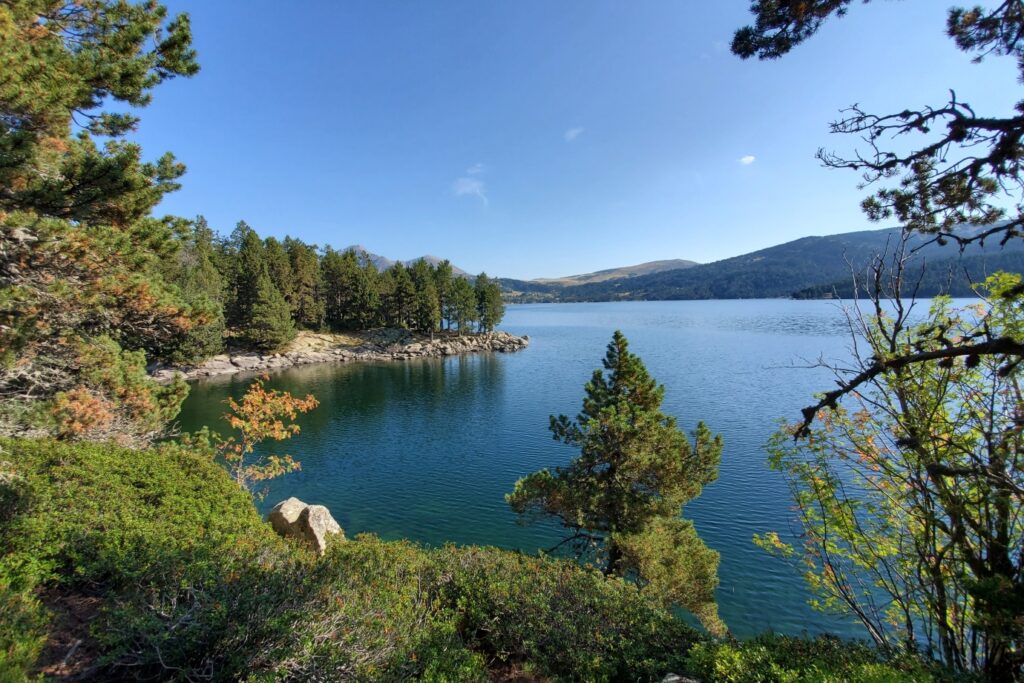 Lac de montagne observé depuis les berges, qui donne une vue sur la montagne et le paysage à côté