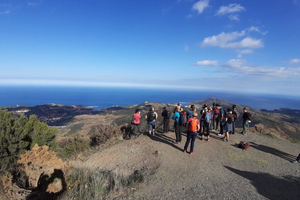 Groupe de randonneurs face à la vue de la côte au cours de leur randonnée