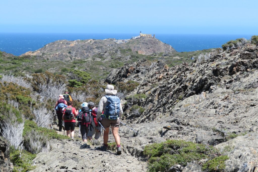 Groupe de randonneurs marchant sur un sentier montagnard de roche grise vers la mer