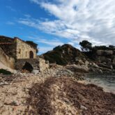 Paysage de bord de mer avec une plage de cailloux ainsi qu'une maison en pierre