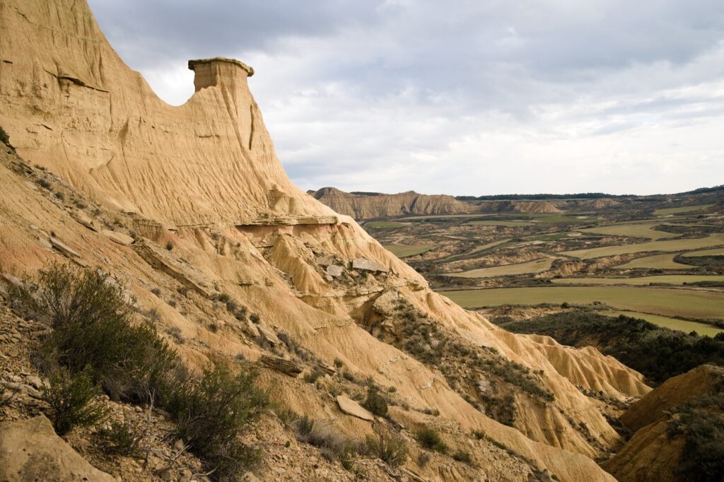 Paysage des Bardenas avec un sommet sec entouré de plaines et de champs de blé qui dépendent de la saison