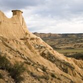 Paysage des Bardenas avec un sommet sec entouré de plaines et de champs de blé qui dépendent de la saison