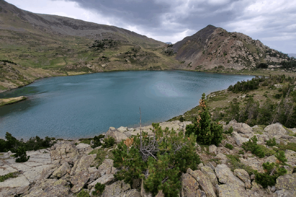 Pasyage de lac de montagne avec en fond des sommets et au premier plan des roches