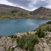Pasyage de lac de montagne avec en fond des sommets et au premier plan des roches