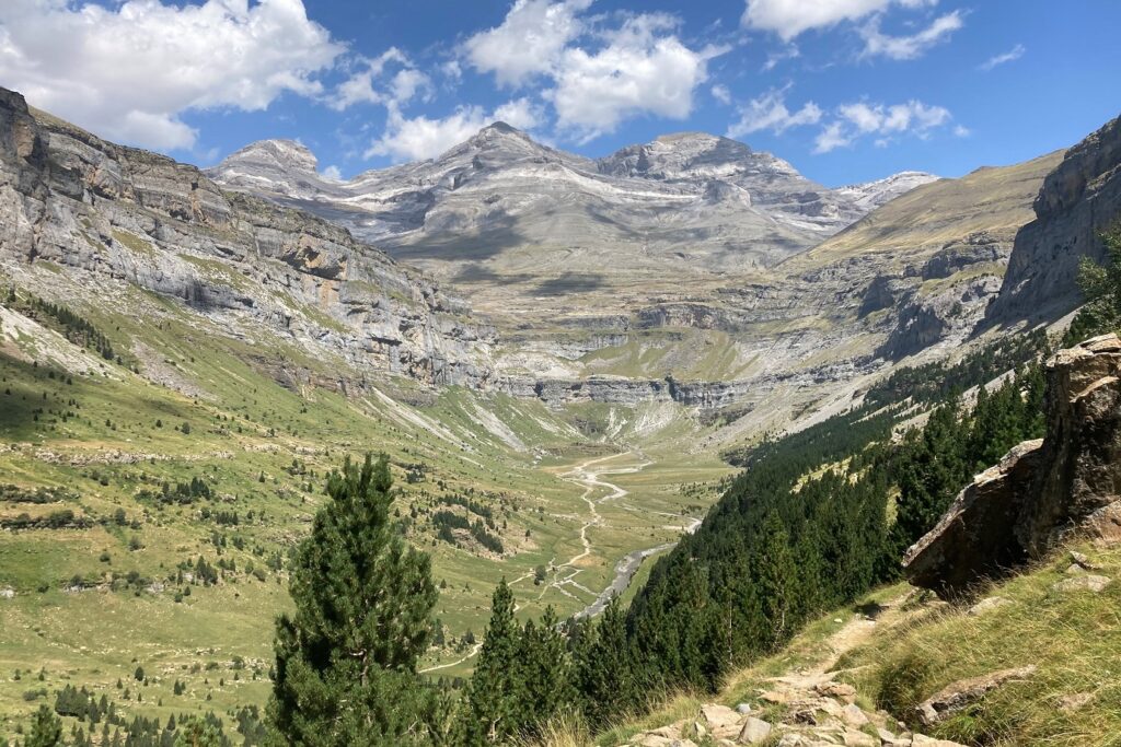 Paysage dans la vallée d'Ordesa, avec en fond des montagnes et des sommets, et au premier plan une forêt et un sentier