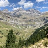 Paysage dans la vallée d'Ordesa, avec en fond des montagnes et des sommets, et au premier plan une forêt et un sentier