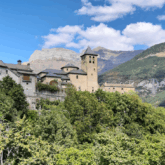 Village perché sur les hauteurs, entouré de végétation et d'arbres, avec des sommets derrière.