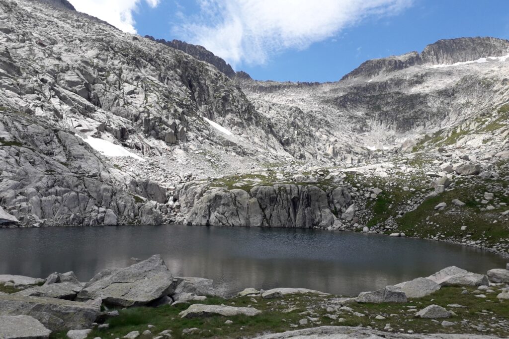 Lac de montagne entouré de montagnes rocheuses aux couleurs grises.
