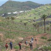 groupe de randonneurs sur un sentier dans les caries, sentier de terre encadré de palmiers et de montagnes au loin