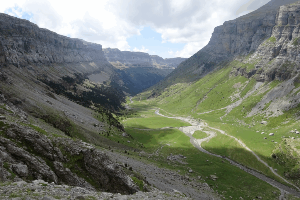 vallée verdoyante avec des chemins entourés de deux falaises montagneuses
