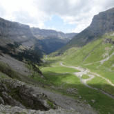 vallée verdoyante avec des chemins entourés de deux falaises montagneuses