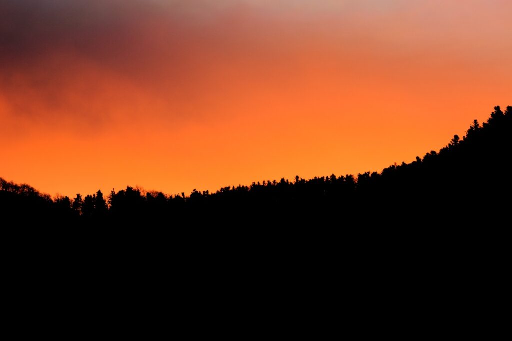 Paysage au coucher du soleil avec des couleurs orangées à contrejour de la montagne