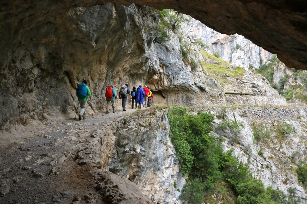 Groupe de randonneurs sur un sentier qui s'avance à flanc de la montagne