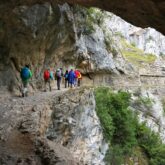 Groupe de randonneurs sur un sentier qui s'avance à flanc de la montagne