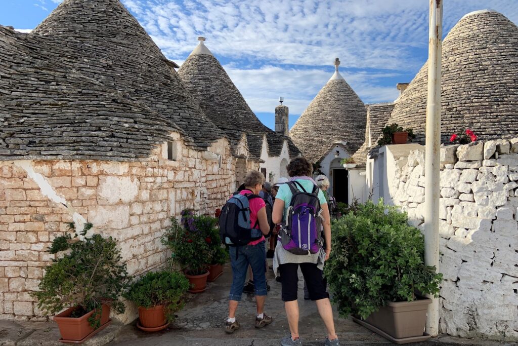 Groupe de randonneurs sur un sentier entre des maisons typiques des Pouilles