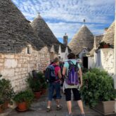 Groupe de randonneurs sur un sentier entre des maisons typiques des Pouilles