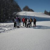 Groupe de randonneurs en raquettes qui ont fait leur trace, avec leur guide, dans la neige.