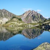 Paysage de montagne avec, au premier plan, un lac et des sommets dans le fond.