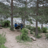 Groupe de personnes se restaurant dans un coin forestier aux abords d'un canyon aux couleurs bleues.