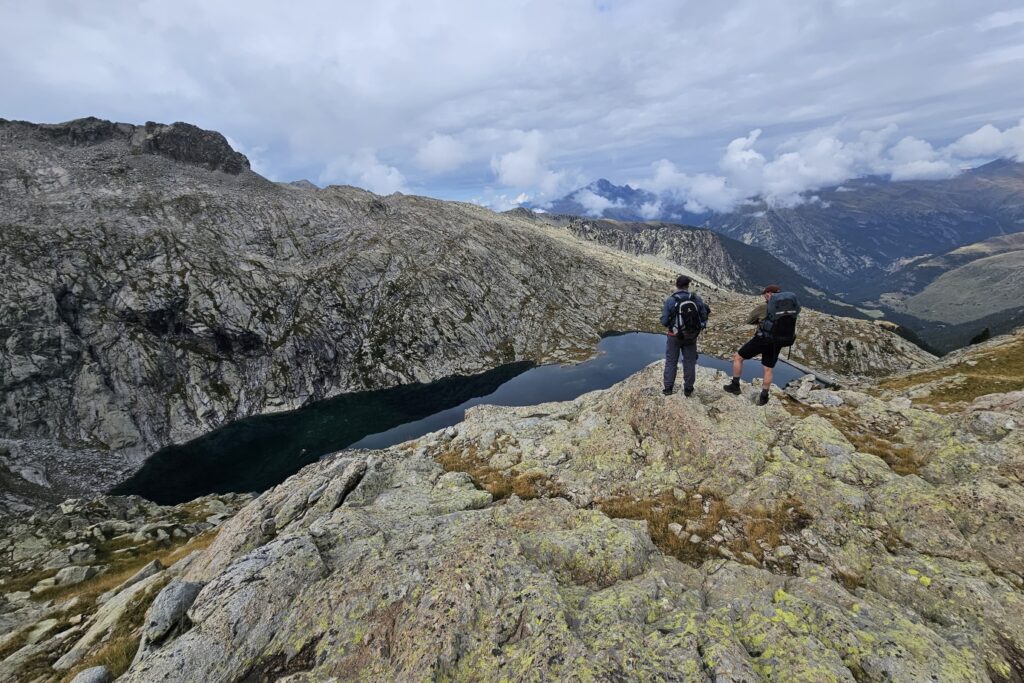 Deux randonneurs face à un lac de montagne qui regardent la vue