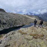 Deux randonneurs face à un lac de montagne qui regardent la vue