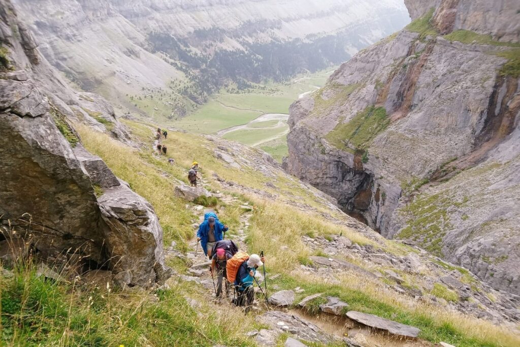 Groupes de randonneurs sur un sentier avec leur guide sur la haute randonnée pyrénéenne entre le Vignemale et les Posets