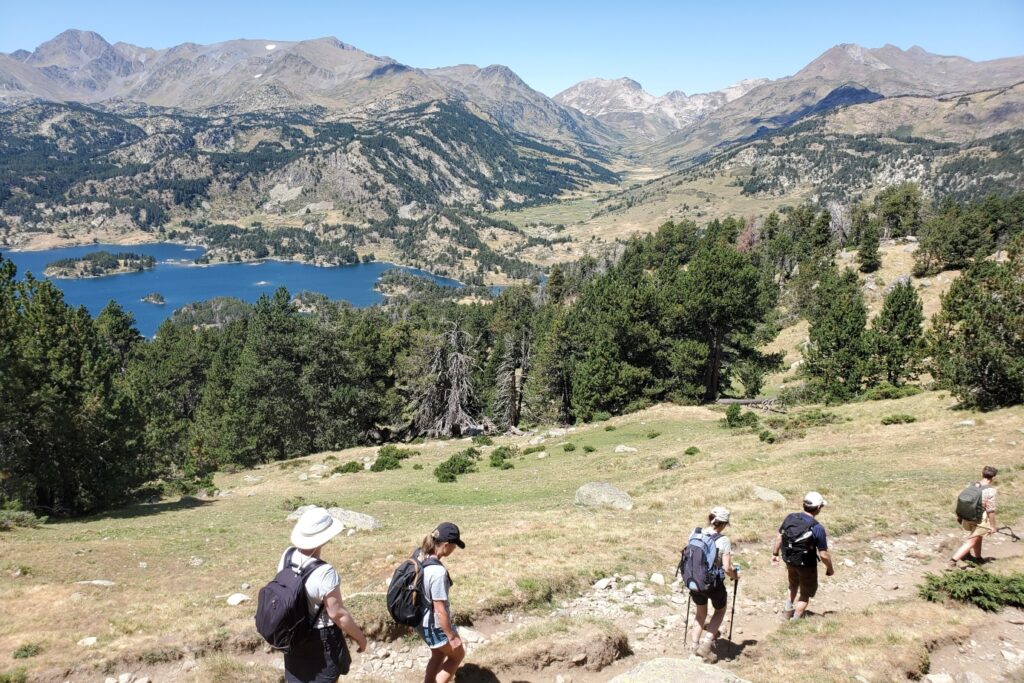 groupe de randonneurs sur un sentier avec leur guide en train de descendre un pan de la montagne