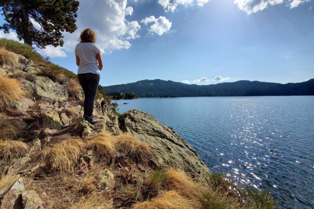 Paysage avec un lac de montagne et une randonneuse qui observe la vue au cours de son séjour en montagne