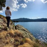 Paysage avec un lac de montagne et une randonneuse qui observe la vue au cours de son séjour en montagne