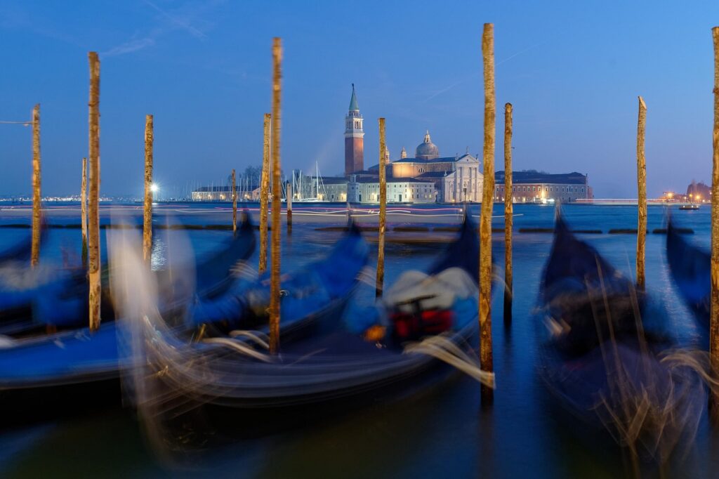 Paysage de nuit à Venise avec les gondoles au port et des constructions en arrière-plan