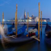 Paysage de nuit à Venise avec les gondoles au port et des constructions en arrière-plan