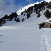 Paysage hivernal avec une trace du groupe en raquette dans la neige et une maison en pierre dans le fond.