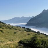 Paysage estival avec une mer de nuages en fond qui couvre la vallée