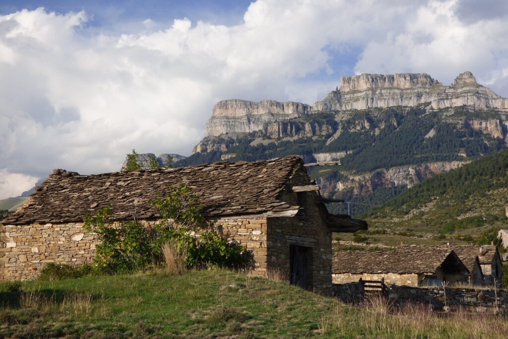 Paysage estival de montagne en Aragon, avec en fond des sommets et au premier plan une maison en pierre