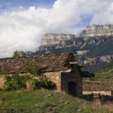 Paysage estival de montagne en Aragon, avec en fond des sommets et au premier plan une maison en pierre