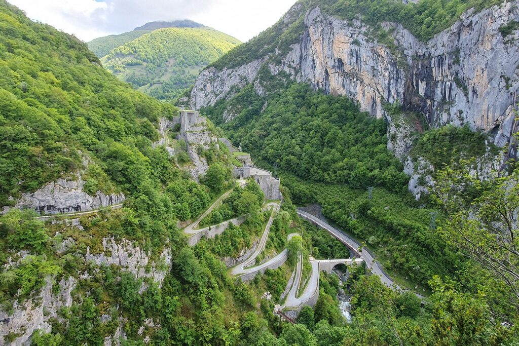 Paysage de montagne avec des falaises ainsi qu'une route qui passe à flanc de la montagne en formant des lacets