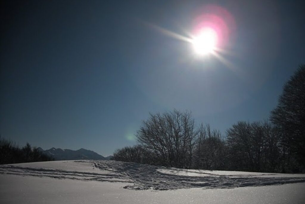 Paysage montagnard sous la neige avec un grand soleil