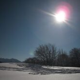 Paysage montagnard sous la neige avec un grand soleil
